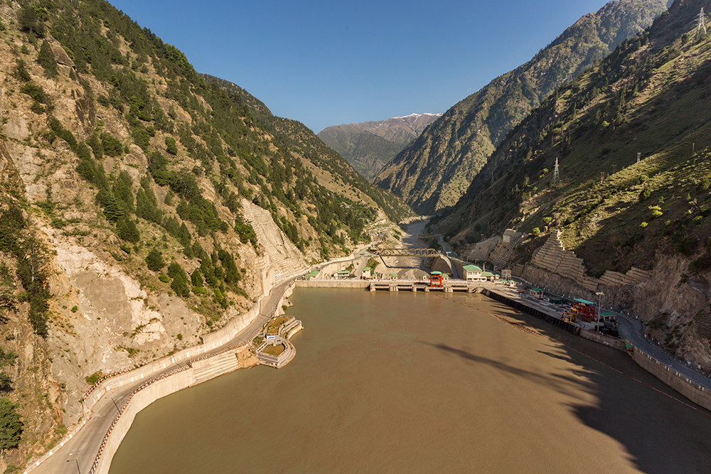 Wasserkraftwerk in einem Tal zwischen bewaldeten Bergen